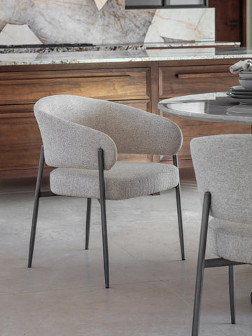 Beige boucle dining chair with black legs in a modern kitchen setting.