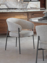 Beige boucle dining chair with black legs in a modern kitchen setting.