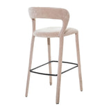Taupe upholstered bar stool with curved backrest and black footrest.