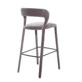 Grey upholstered bar stool with curved backrest and sleek metal footrest.