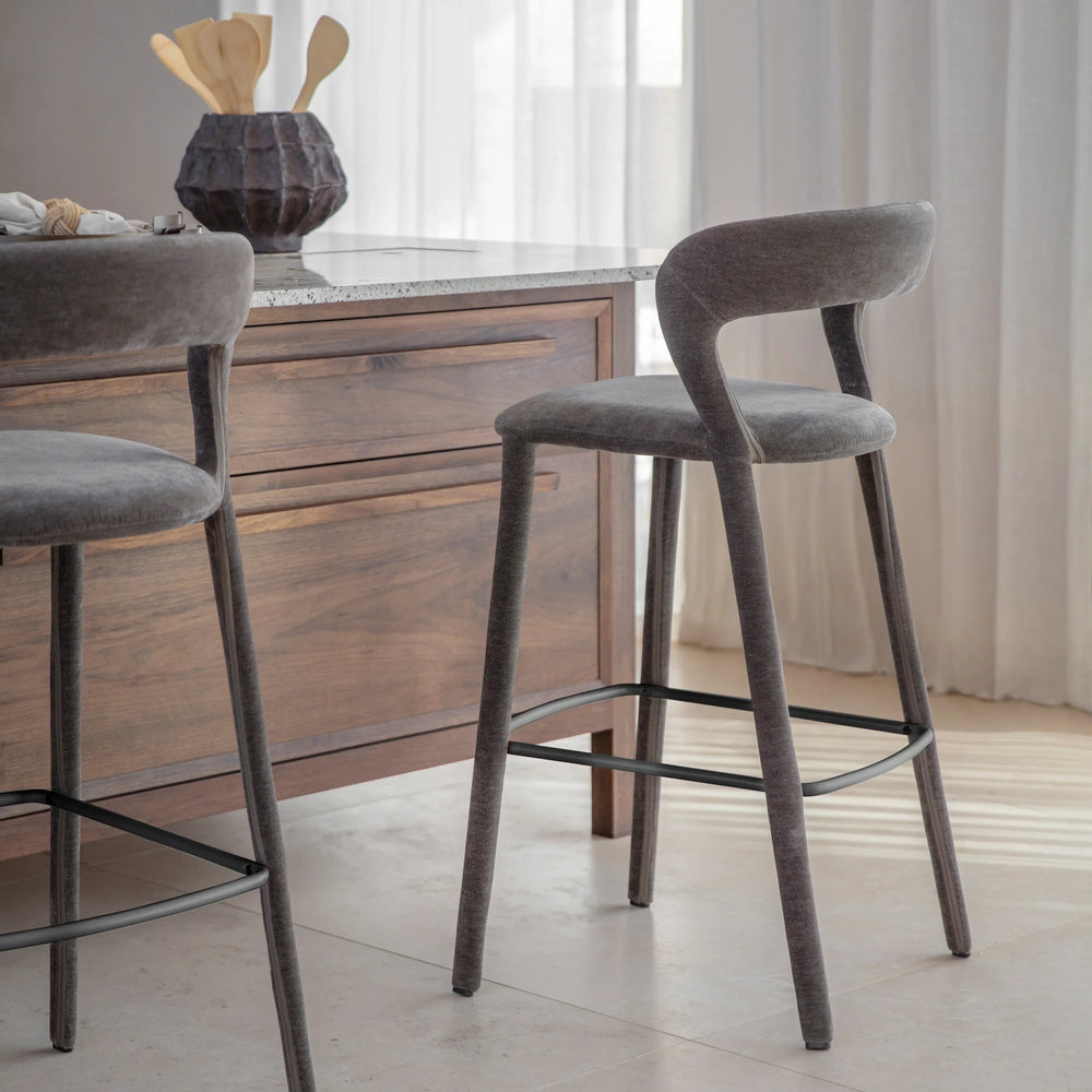 Grey upholstered bar stool beside wooden kitchen island.