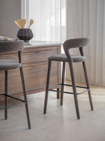 Grey upholstered bar stool beside wooden kitchen island.