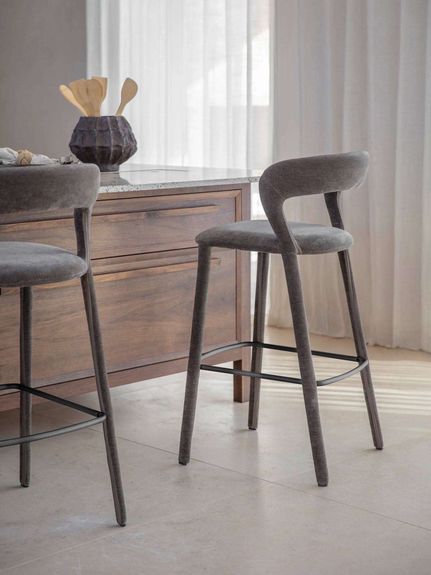 Grey upholstered bar stool beside wooden kitchen island.