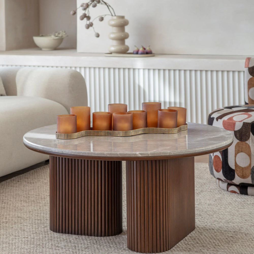 Round coffee table with ribbed wooden base and marble top in cozy living room.