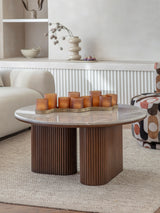 Round coffee table with ribbed wooden base and marble top in cozy living room.