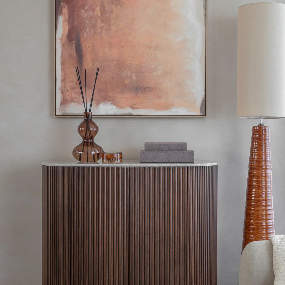 Dark wood cabinet in a living room with abstract art and a tall lamp.