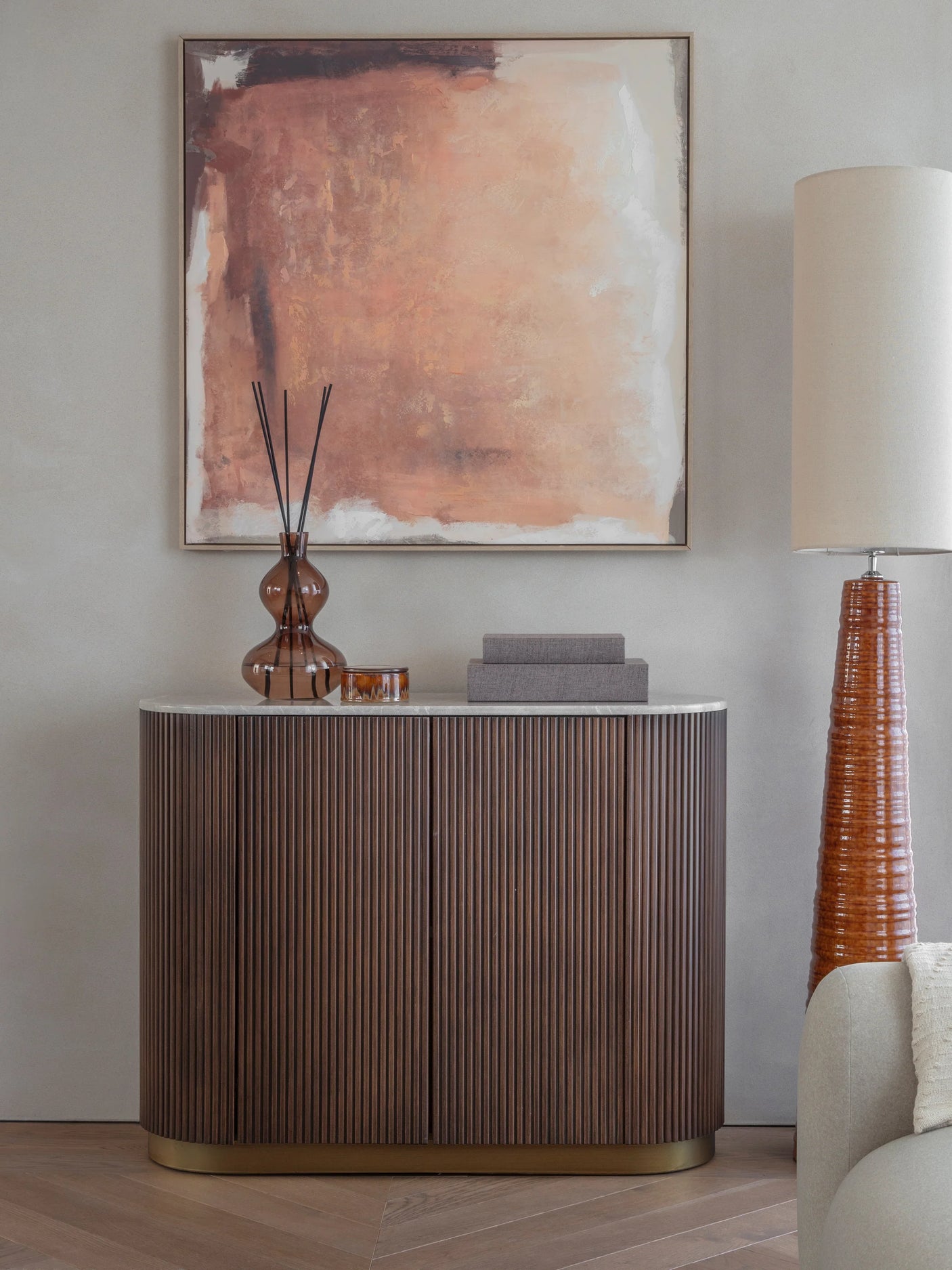 Dark wood cabinet in a living room with abstract art and a tall lamp.