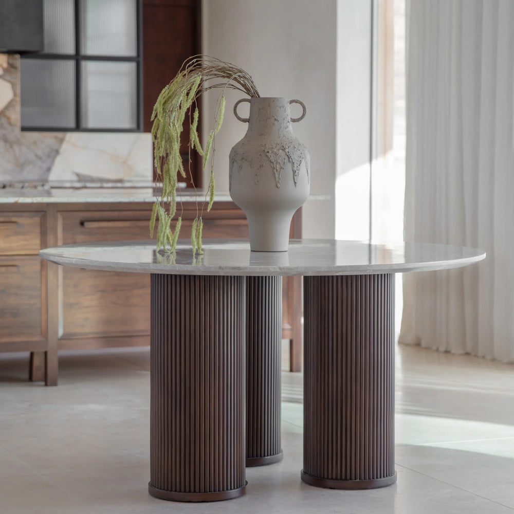 Marble-topped table with ribbed wooden legs in a sunlit dining room.