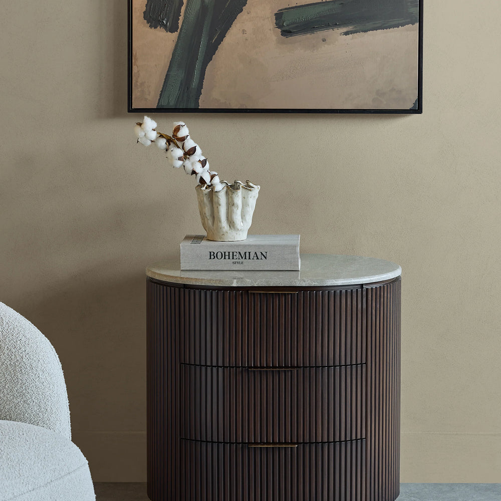 Dark wood bedside chest with ribbed texture in a stylish room setting.