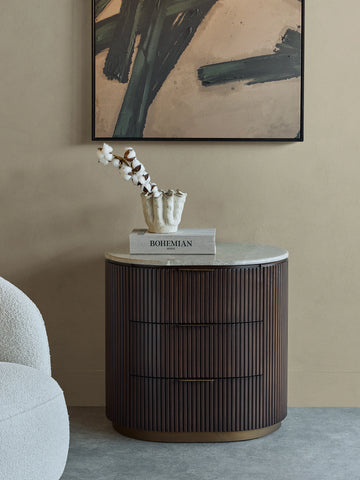 Dark wood bedside chest with ribbed texture in a stylish room setting.