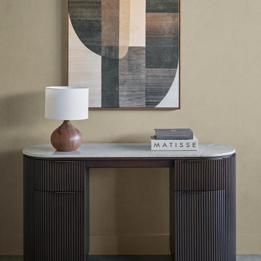 Dark wood desk with ribbed texture, marble top, lamp, and books in a modern room.