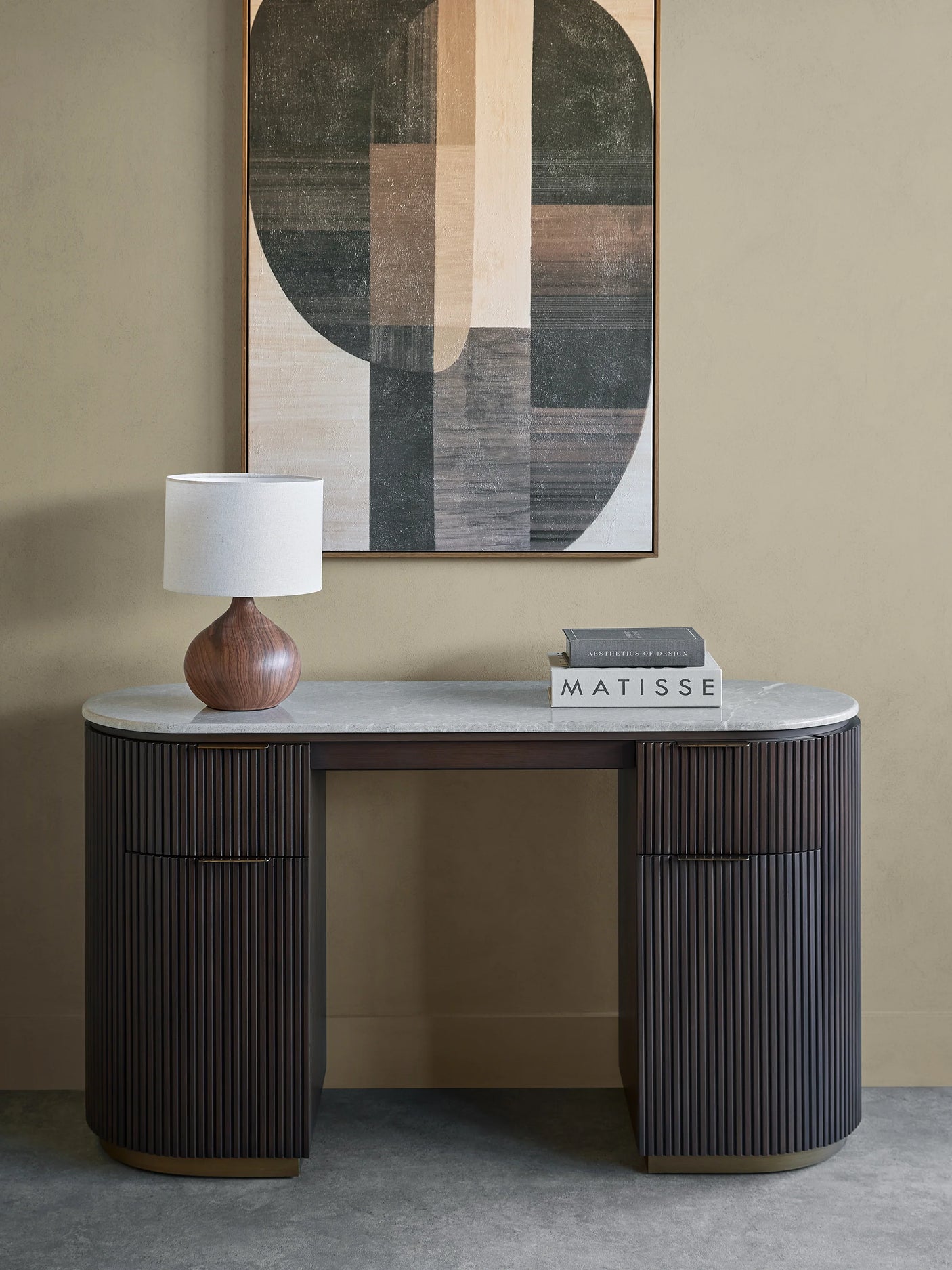 Dark wood desk with ribbed texture, marble top, lamp, and books in a modern room.