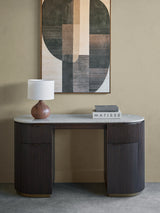 Dark wood desk with ribbed texture, marble top, lamp, and books in a modern room.