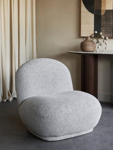 Gray textured chair in a modern room with a vase and abstract art.