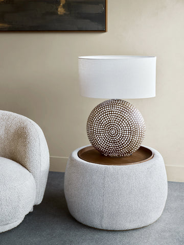 Oatmeal ottoman with decorative lamp in a modern living room setting.