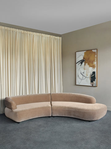 Curved mocha velvet sofa in a modern living room with abstract art.