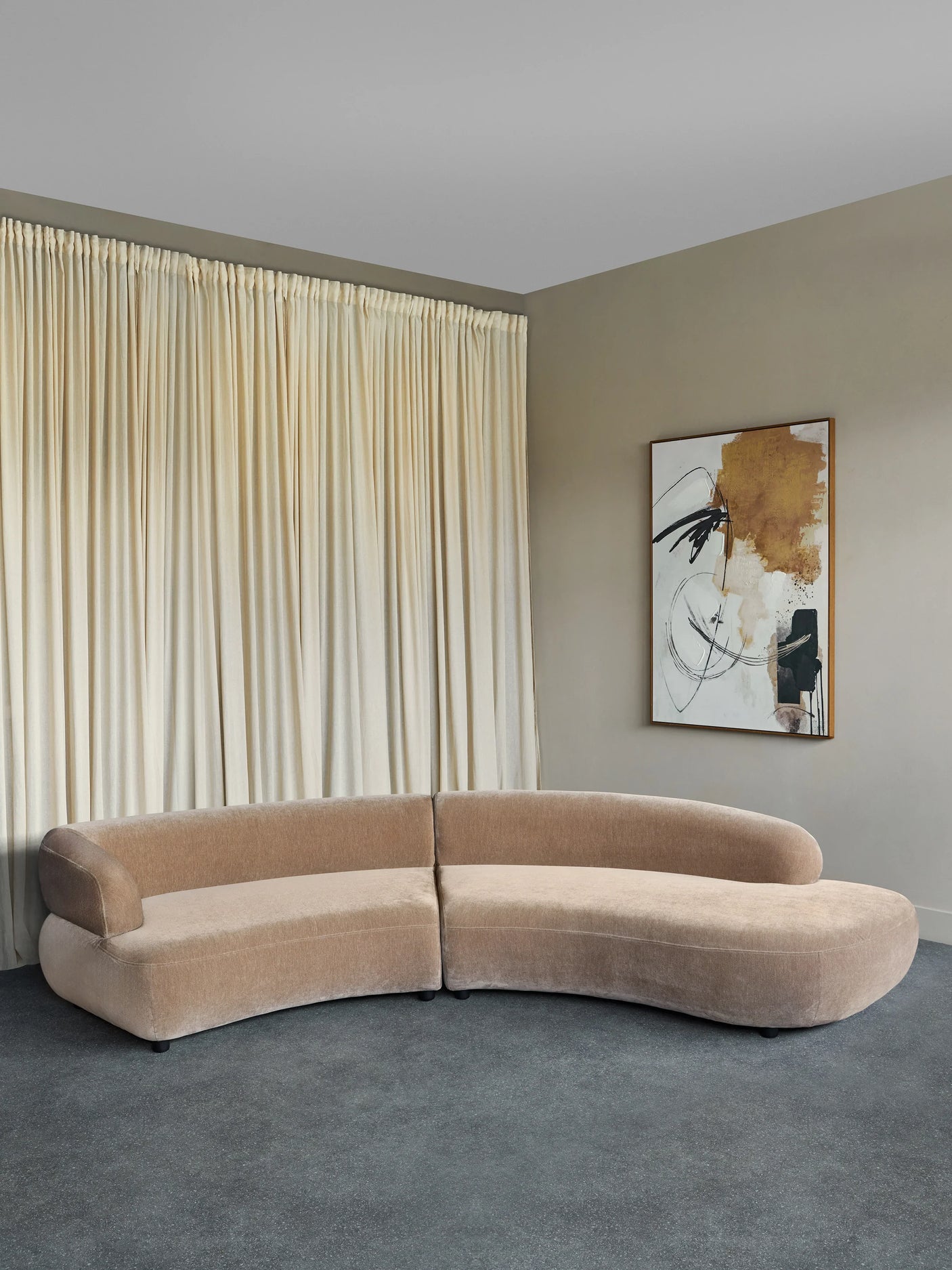 Curved mocha velvet sofa in a modern living room with abstract art.
