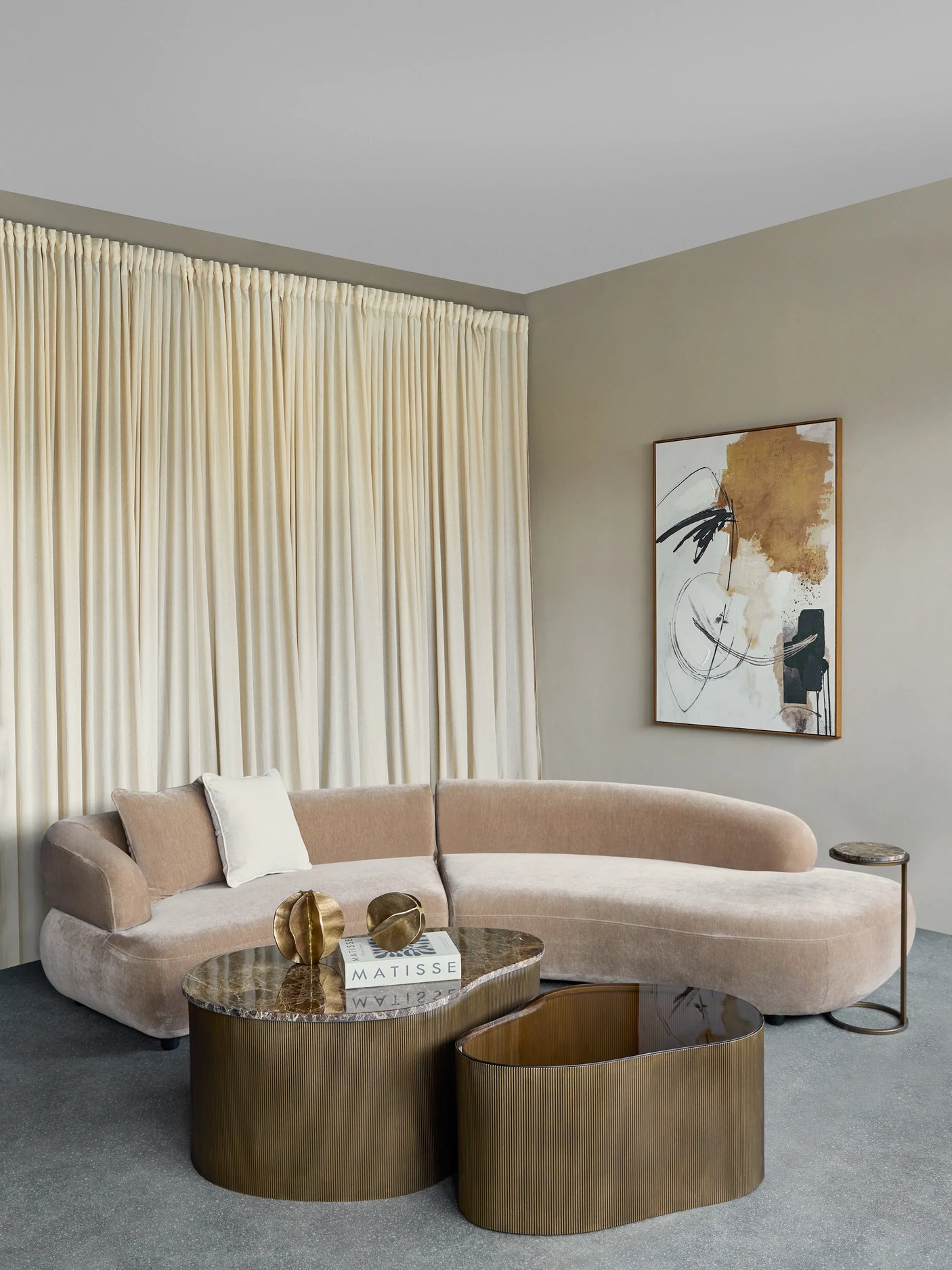 Mocha velvet sofa in elegant living room with abstract art and gold tables.