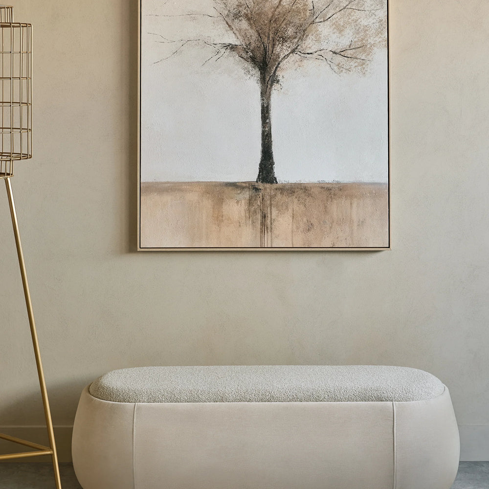 Beige upholstered bench beneath abstract tree painting in a minimalist room.