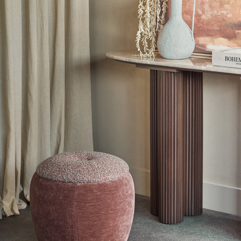 Terracotta storage stool in elegant room with a marble console and decorative vase.