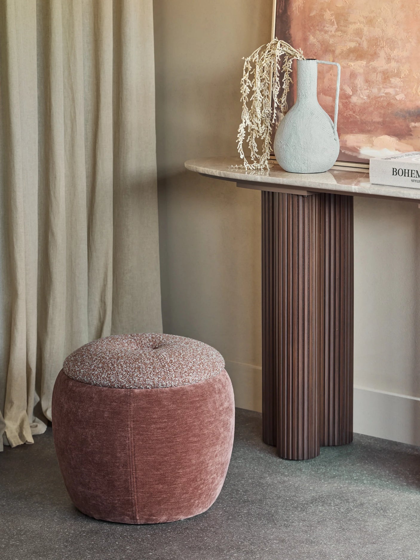 Terracotta storage stool in elegant room with a marble console and decorative vase.