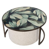 Round coffee table with floral glass top and textured pouffe base.