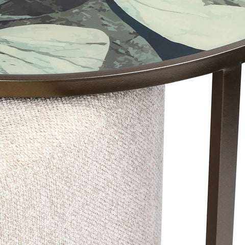 Beige textured pouffe with leaf-patterned table surface above.