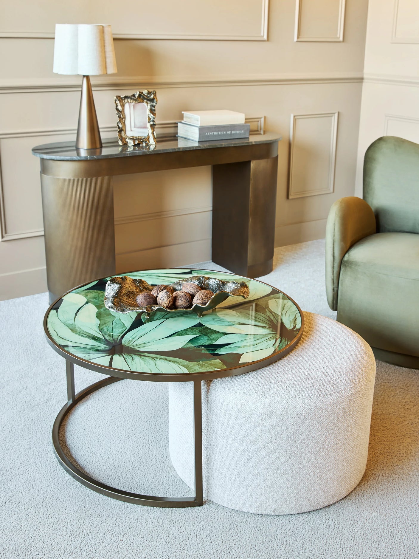 Leaf-patterned glass table with white pouffe in elegant living room setting.
