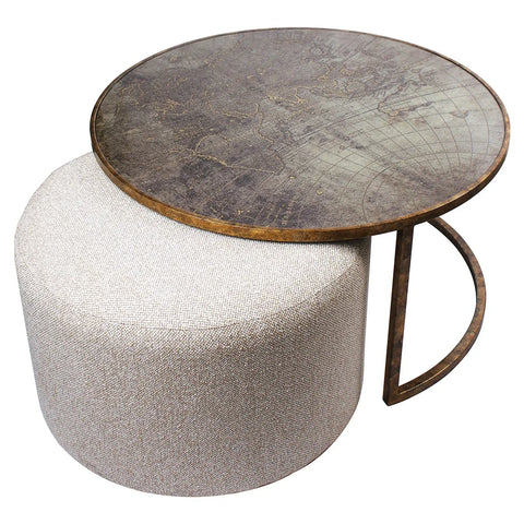 Round metal coffee table with world map design on beige pouffe.