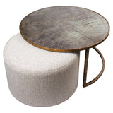 Round metal coffee table with world map design on beige pouffe.