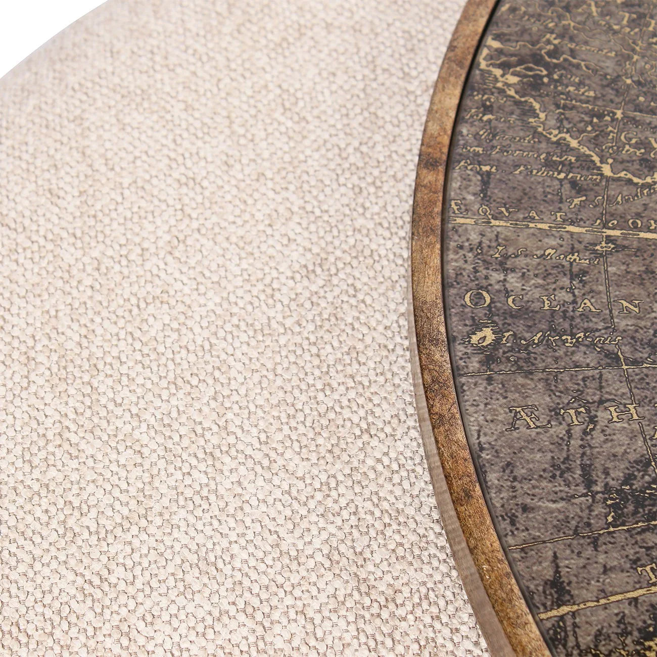Beige textured pouffe beside a wooden map-themed table edge.