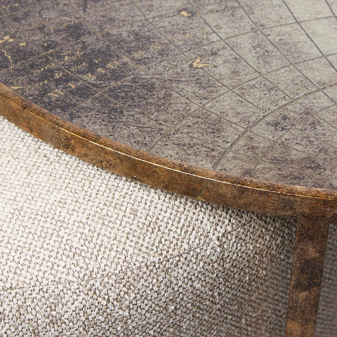 Close-up of a textured beige pouffe with a weathered map-patterned tabletop.