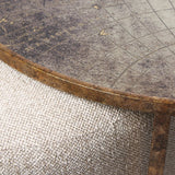 Close-up of a textured beige pouffe with a weathered map-patterned tabletop.