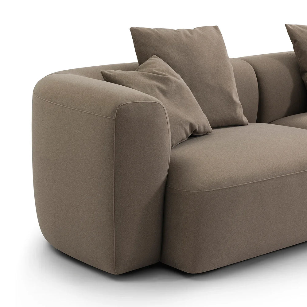 Soft truffle velvet sofa with plush cushions and rounded armrest.