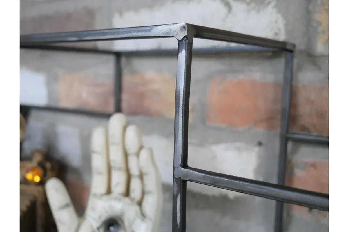 Close-up of black metal shelf frame details against brick wall