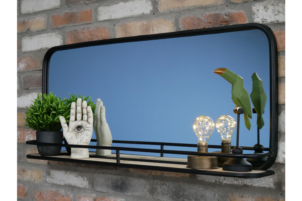 Black-framed rectangular wall mirror with wooden shelf featuring plant, decorative hands, light bulbs, and bird sculptures.