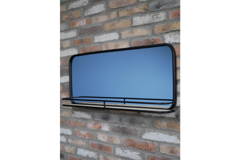 Wall-mounted rectangular mirror with black metal frame and wooden shelf in front, shown at slight angle.