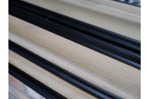 Close-up detail of light wood and black frame shelf edge on mirror with shelf at an angle.