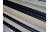 Close-up detail of light wood and black frame shelf edge on mirror with shelf at an angle.