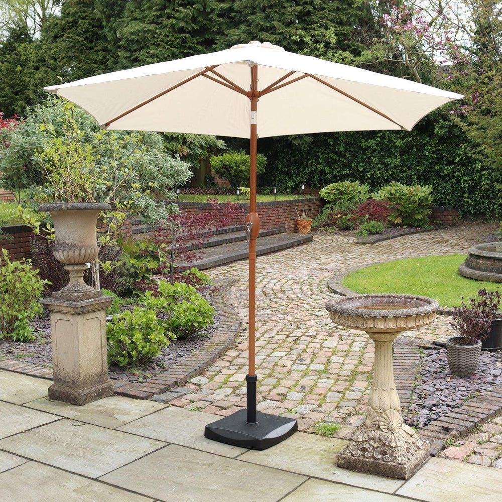 Cream outdoor parasol with wooden pole on stone patio in garden setting
