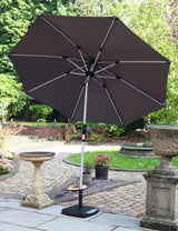 Grey garden parasol with metal frame and crank base on patio beside stone bird bath