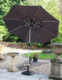 Grey garden parasol with metal frame and crank base on patio beside stone bird bath