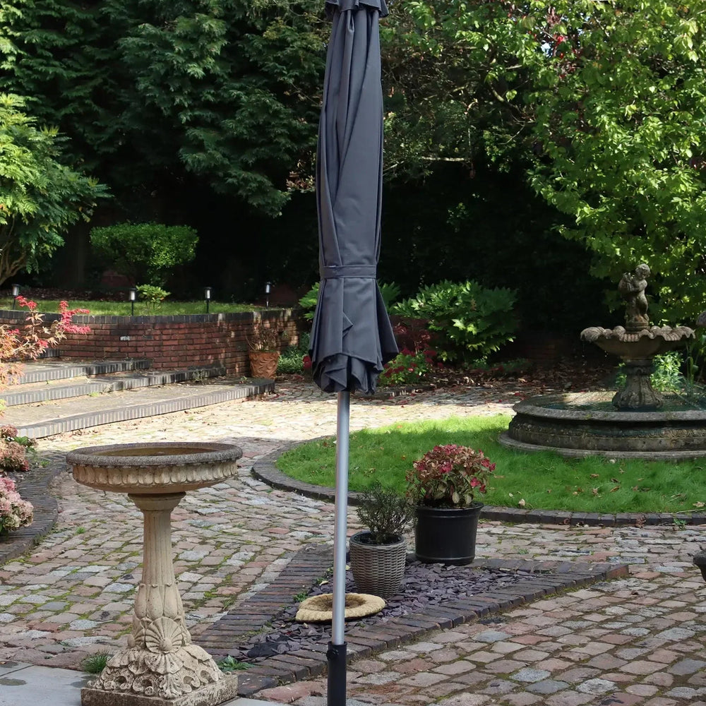 Grey garden parasol with metal pole and base on stone patio in landscaped backyard