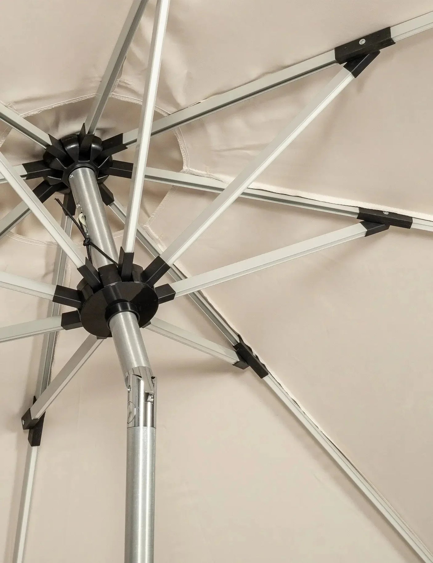 Close up of outdoor parasol frame with silver metal ribs and beige canopy fabric