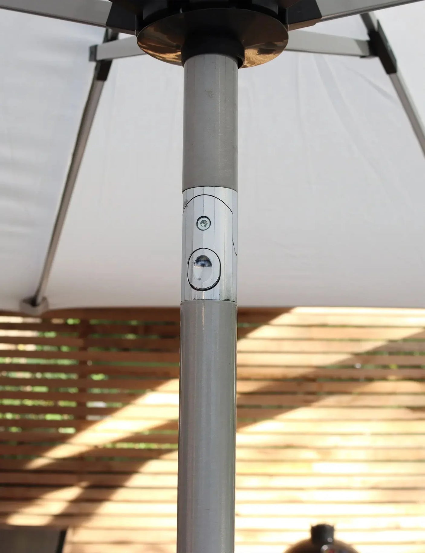 Close up of outdoor parasol pole with tilt mechanism beneath white canopy