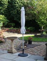 Closed outdoor garden parasol with white canopy and black base on stone patio