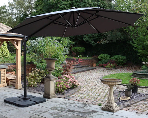 Large black cantilever garden parasol on patio with paved path and landscaped plants