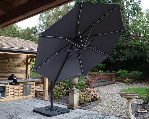 Large grey cantilever garden parasol on patio beside outdoor kitchen and landscaped garden