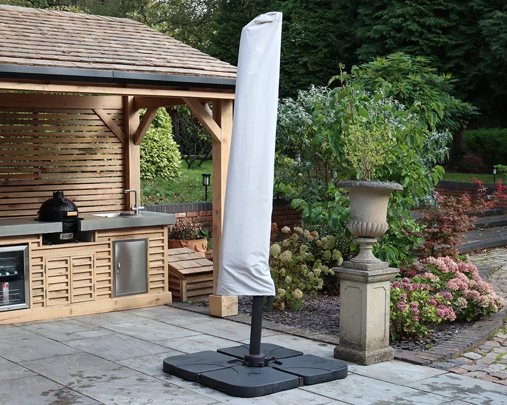 Garden parasol with protective cover beside outdoor kitchen and patio planters