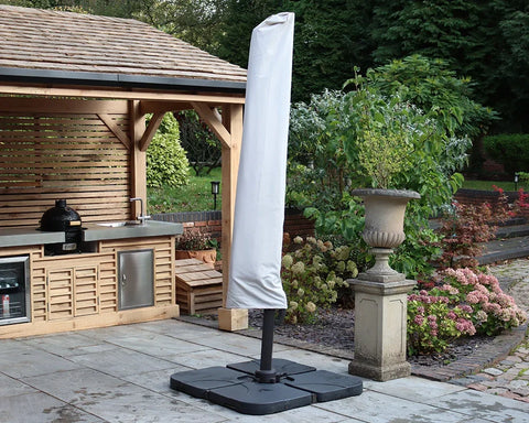 Garden parasol with protective cover beside outdoor kitchen and patio planters